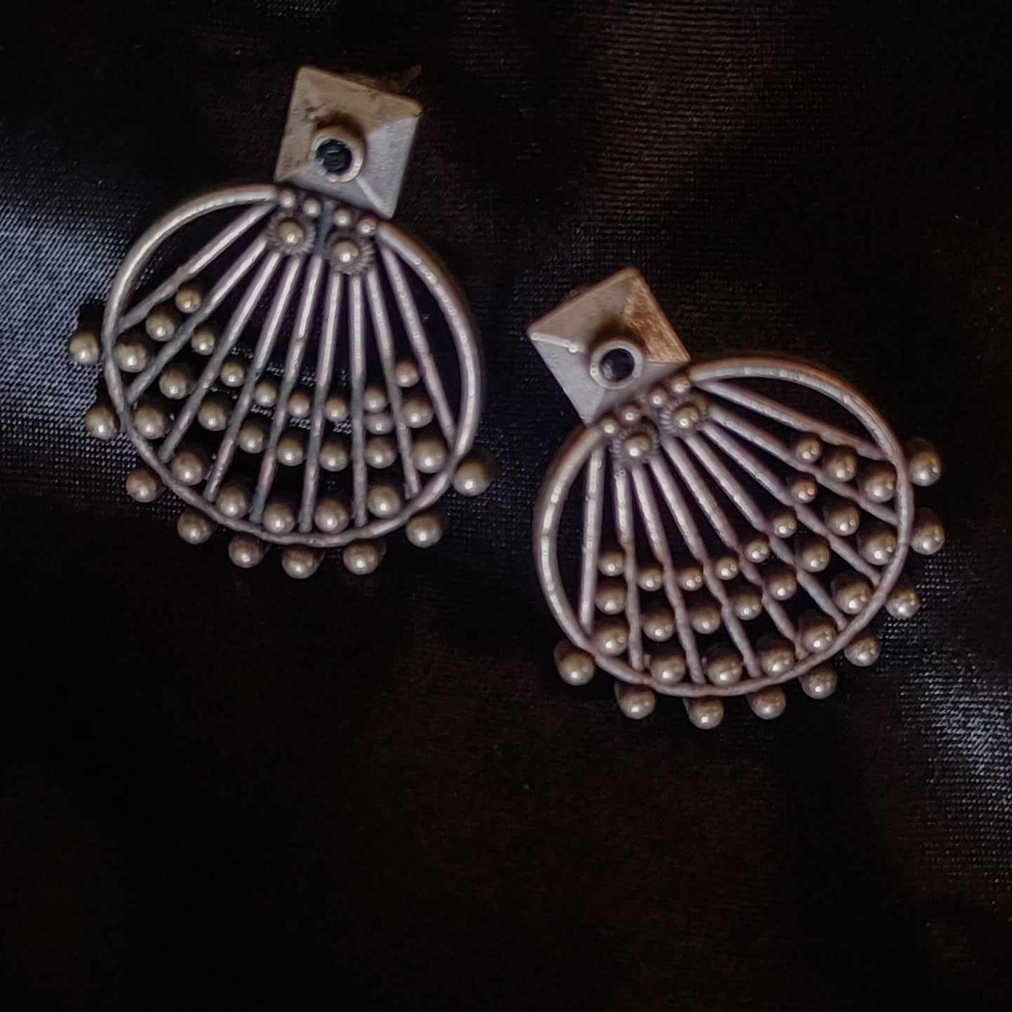 Pair of silver earrings on a dark fabric background