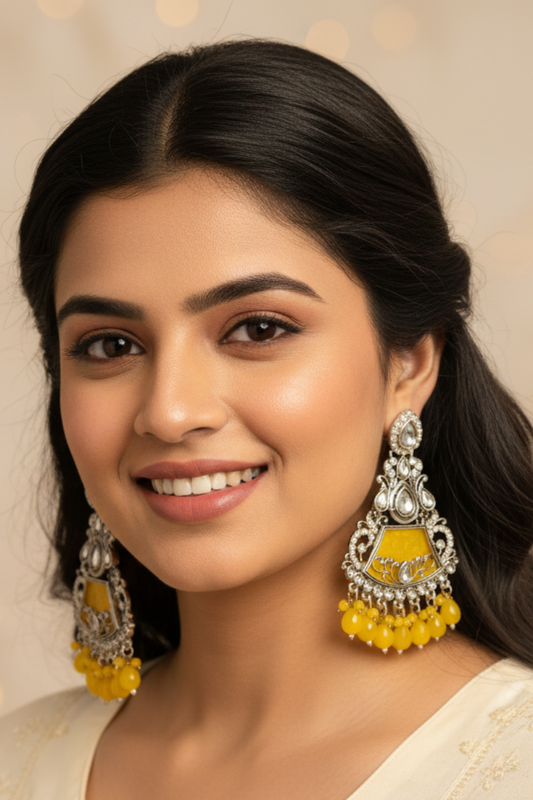 Woman wearing yellow and silver earrings against a warm-toned background