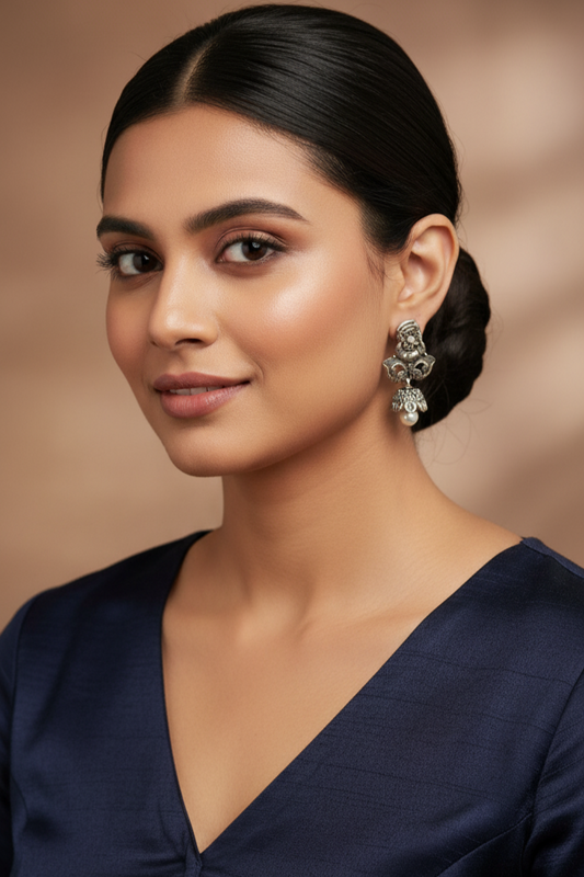 Woman wearing a navy blue outfit with earrings against a warm brown background