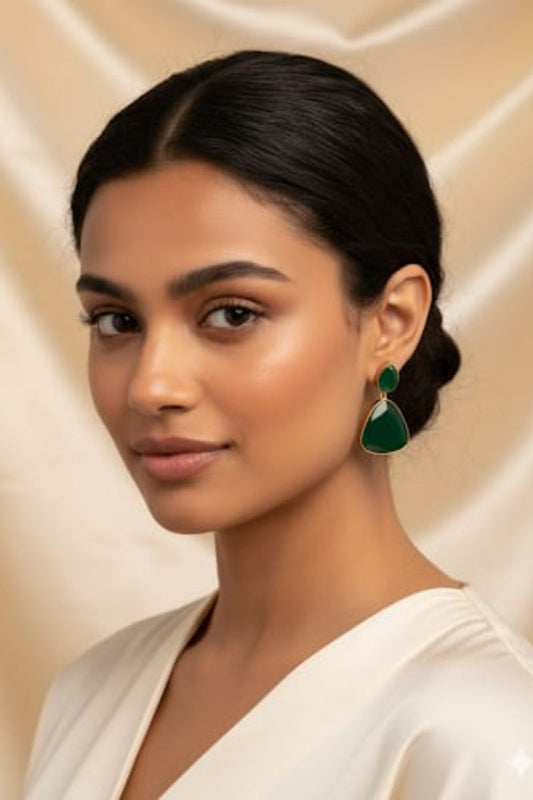 Woman wearing green earrings against a beige background