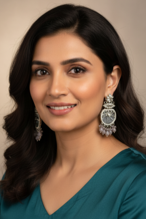 Woman wearing a teal dress with silver earrings against a neutral background